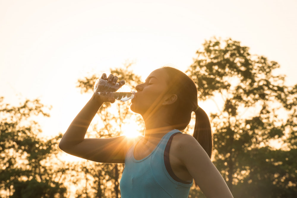Ser saúdavel - Mulher bebe água depois de praticar exercício físico ao ar livre.